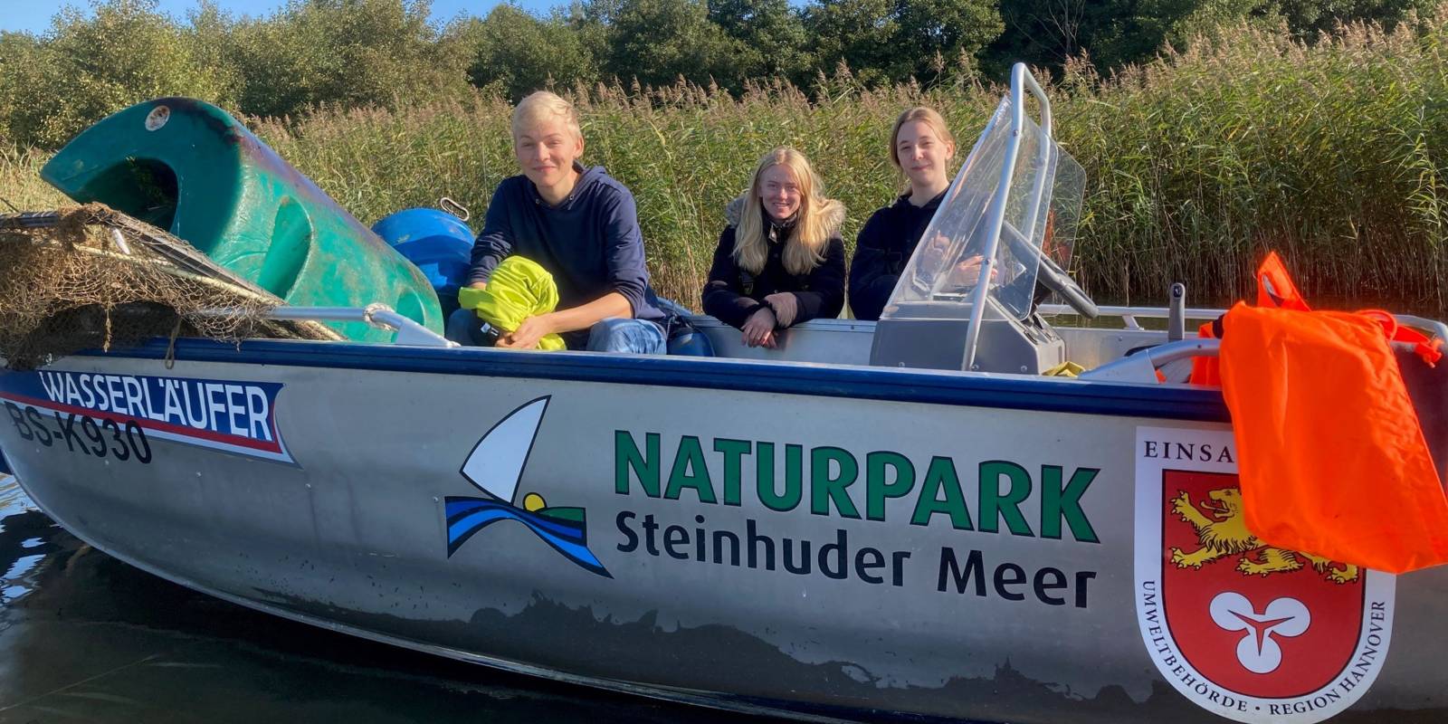 Drei junge Menschen in einem Boot auf dem "Naturpark Steinhuder Meer" steht